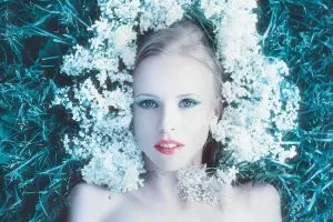 Blada kobieta blondynka leżąca z białymi kwiatami wokół twarzy